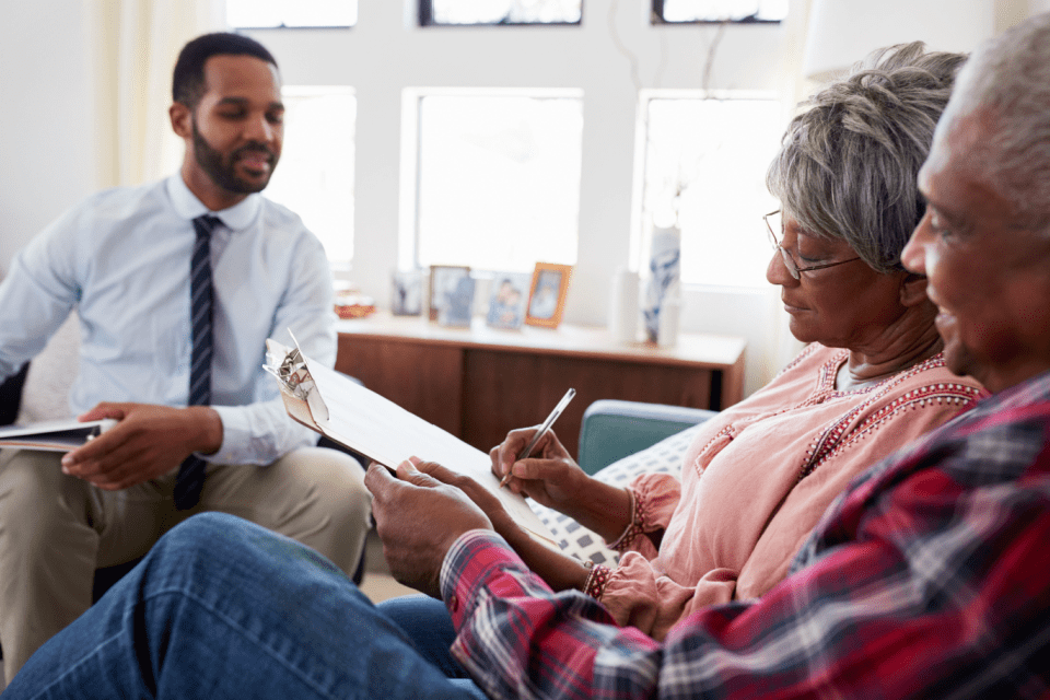 Senior couple meeting with a financial advisor at home and signing a document.